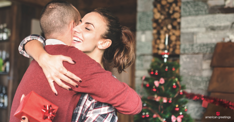 Young couple hugging in front of a Christmas tree, she